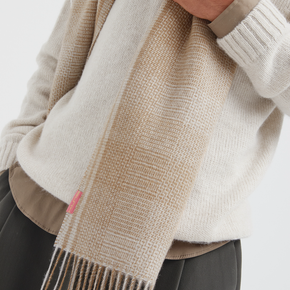 Person wearing a beige sweater and scarf with a white background
