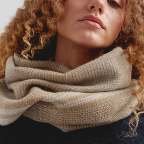 Close-up of a person wearing a beige scarf with a neutral background