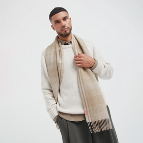 Man wearing a beige scarf and white sweater on a white background