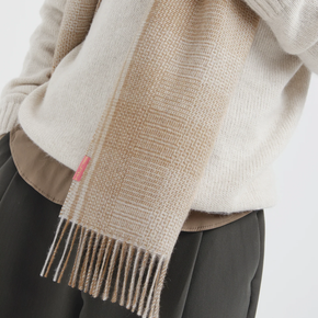 Beige sweater and scarf with a pink tag on a neutral background