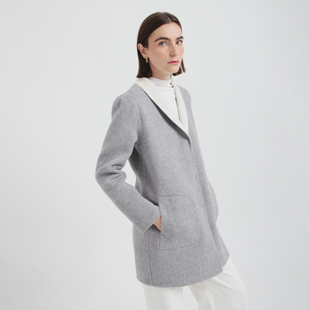 Person wearing a gray jacket over a white shirt on a light gray background