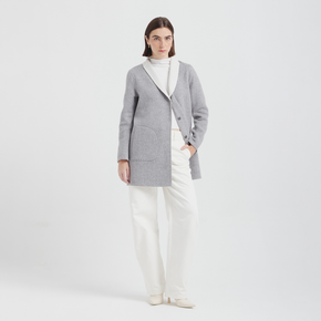 Woman wearing a gray jacket over a white top and pants on a light gray background