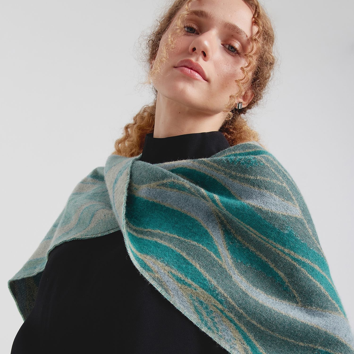Woman wearing a teal and gray patterned scarf against a white background