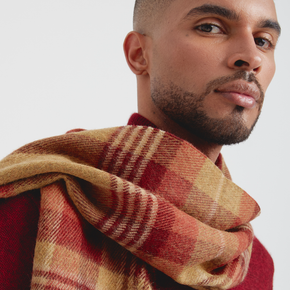 Man wearing a plaid scarf with a neutral background