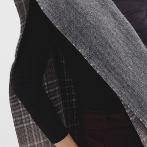 Close-up of a person wearing a dark scarf with plaid pattern on a white background