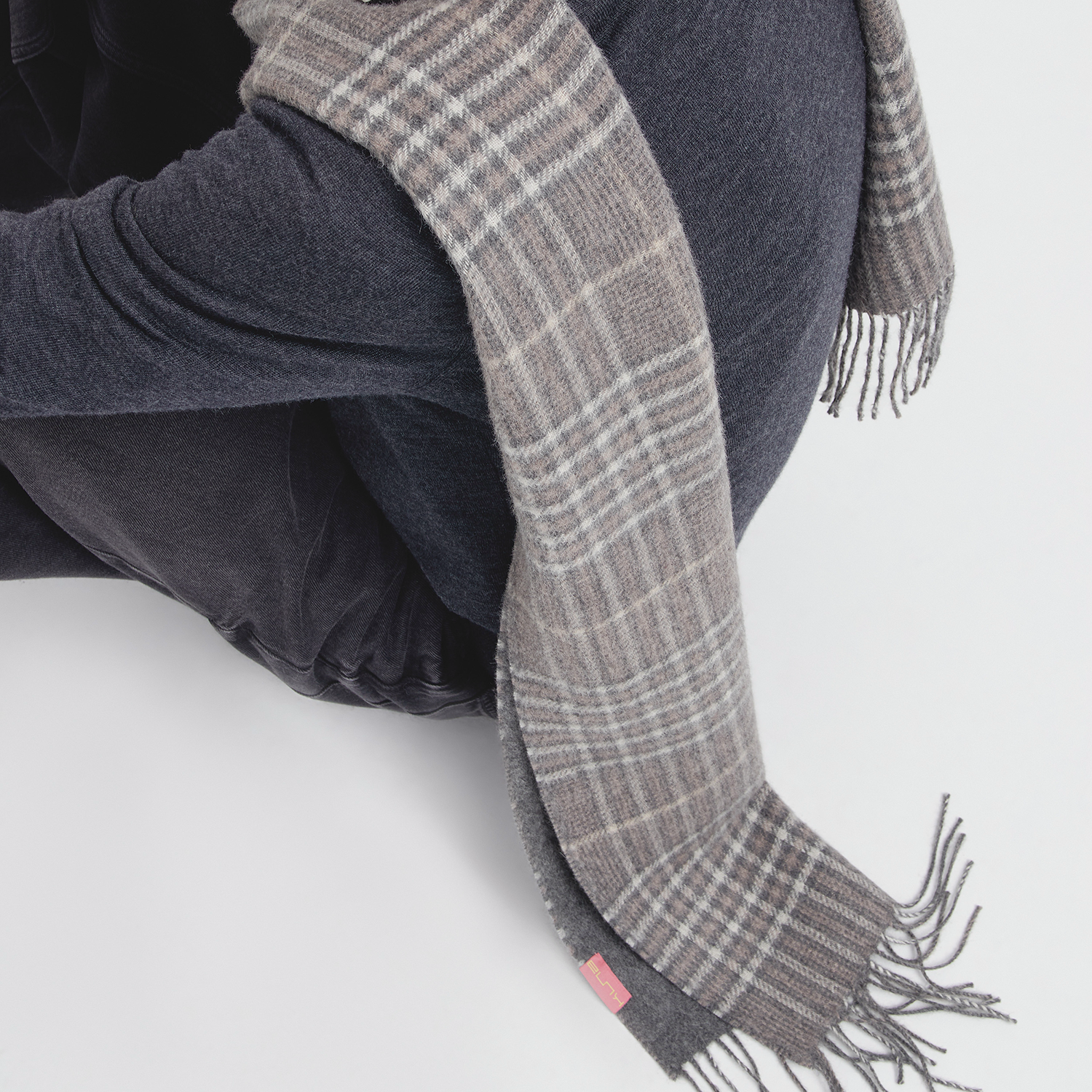 Person wearing a gray plaid scarf with a white background