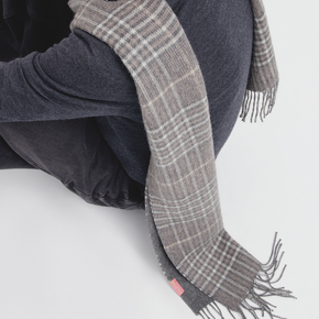 Person wearing a gray plaid scarf with a white background