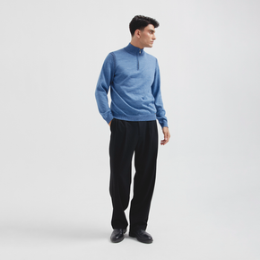 Man wearing a blue sweater and black pants on a white background