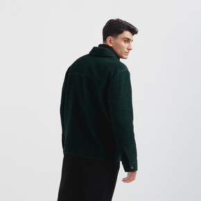 Man wearing a dark green jacket on a light gray background