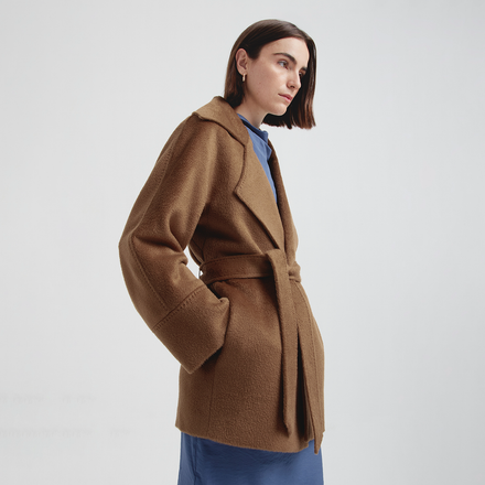 Woman wearing a brown coat on a plain background