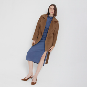 Woman wearing a brown coat and blue dress on a white background