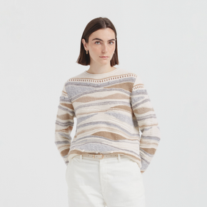 Woman wearing a striped sweater and white pants on a plain background
