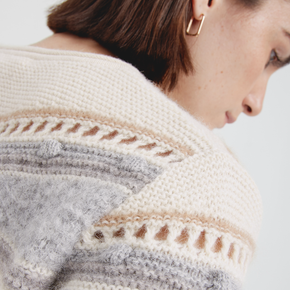 Close-up of a person wearing a patterned sweater with a neutral background
