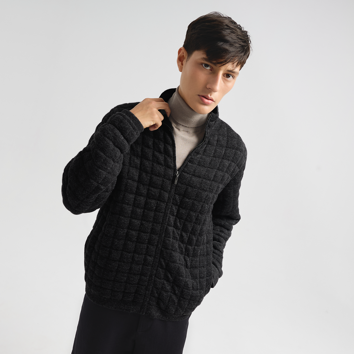 Person wearing a charcoal quilted jacket on a light gray background