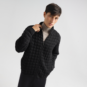 Person wearing a charcoal quilted jacket on a light gray background