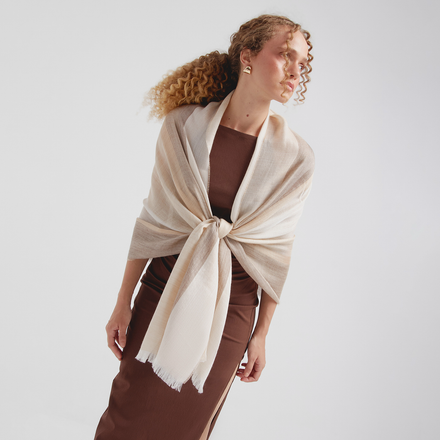 Woman wearing a beige shawl over a brown outfit on a white background