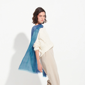 Woman wearing a blue and white sweater with a blue scarf on a white background