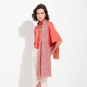 Woman wearing a coral blouse and pink scarf on a white background