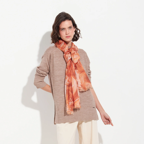 Woman wearing a beige sweater and orange scarf on a white background