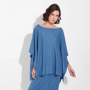 Woman wearing a blue poncho against a white background