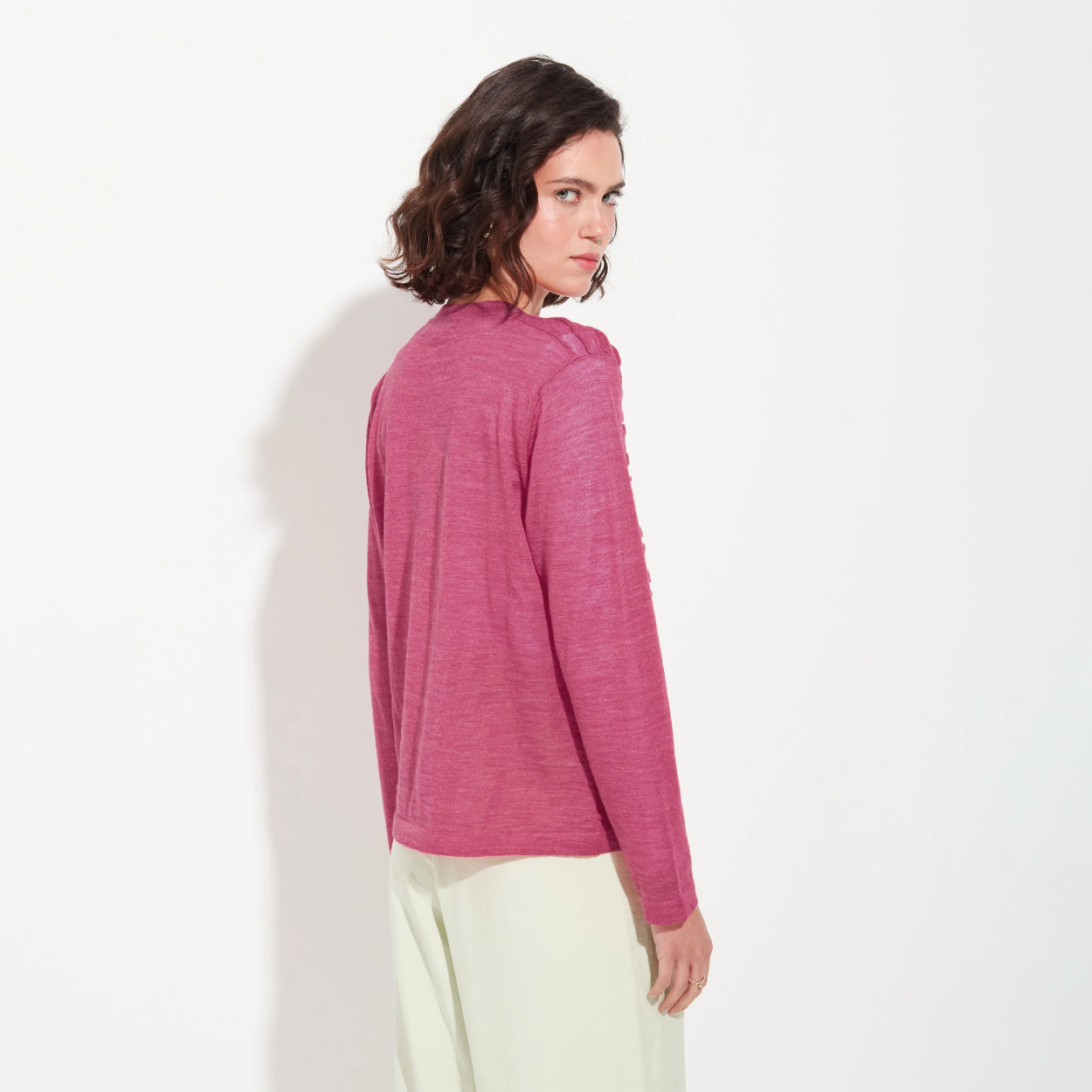 Woman wearing a pink long-sleeve top against a white background