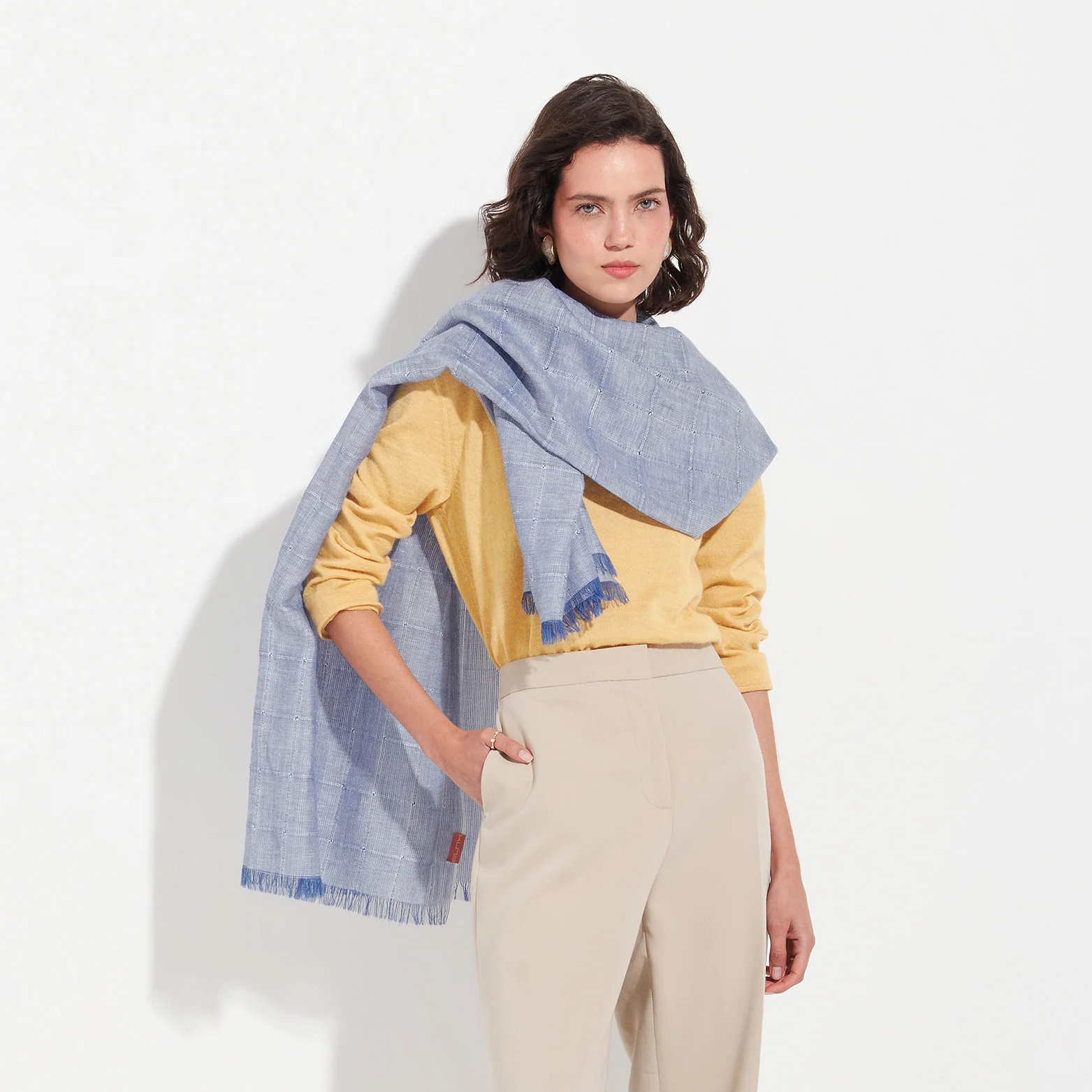 Woman wearing a blue scarf and yellow top on a white background