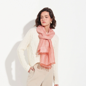 Woman wearing an orange scarf and white sweater on a light background