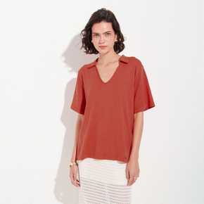 Woman wearing a rust-colored blouse and white skirt on a white background