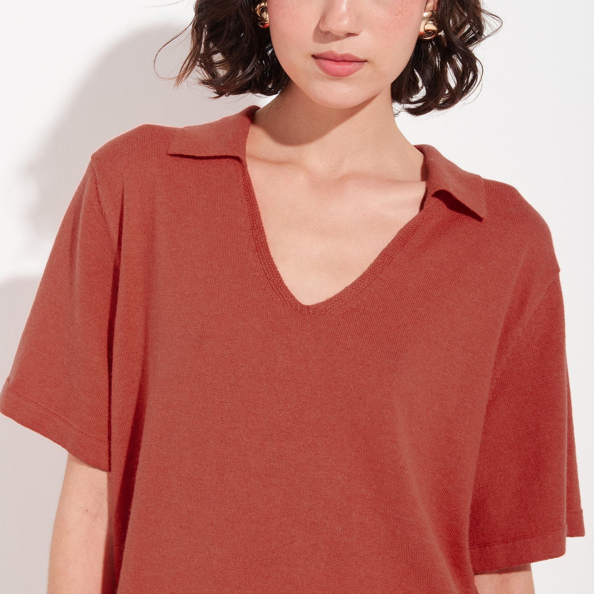 Person wearing a rust-colored polo shirt against a white background