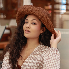 Woman wearing a brown crocheted sun hat in an indoor setting