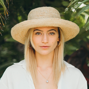 Woman wearing a straw hat with a blurred green background