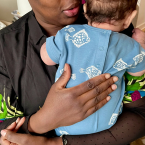 Woman holding a baby wearing a blue outfit with white patterns