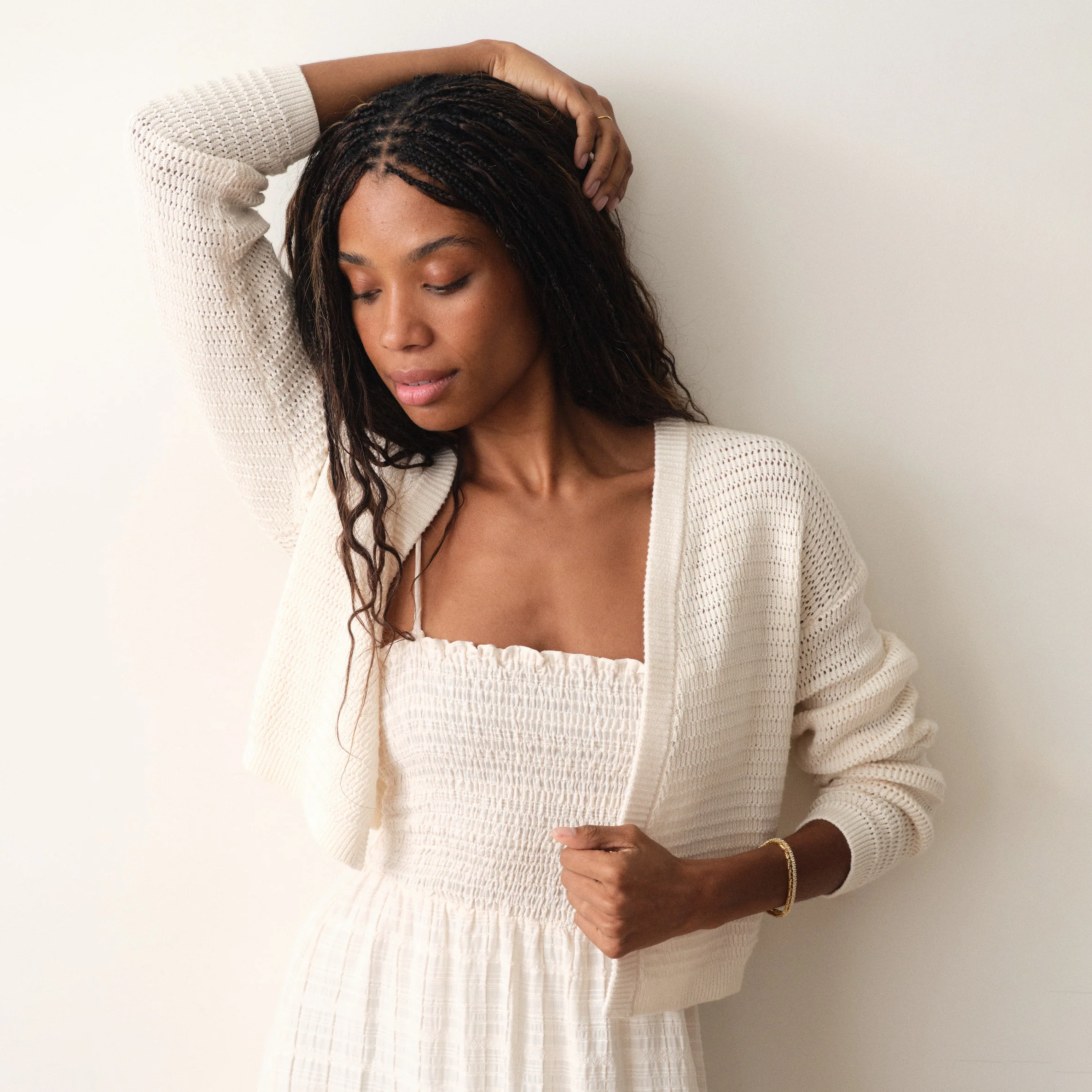 Woman wearing a white dress and cardigan against a plain background