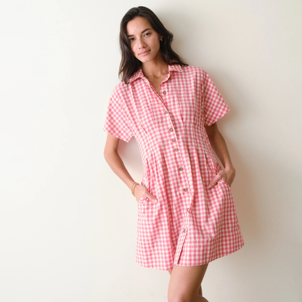 Woman wearing a pink checkered dress against a white background