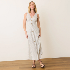 Woman wearing a white and gray striped dress with buttons on a plain background