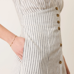 Close-up of a person wearing a striped dress with button details on a plain background