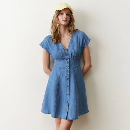 Woman wearing a blue dress with a yellow cap against a white background