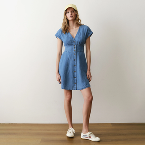 Woman wearing a blue dress and white sneakers on a plain background