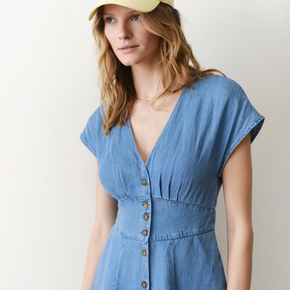 Woman wearing a blue denim dress with a plain background
