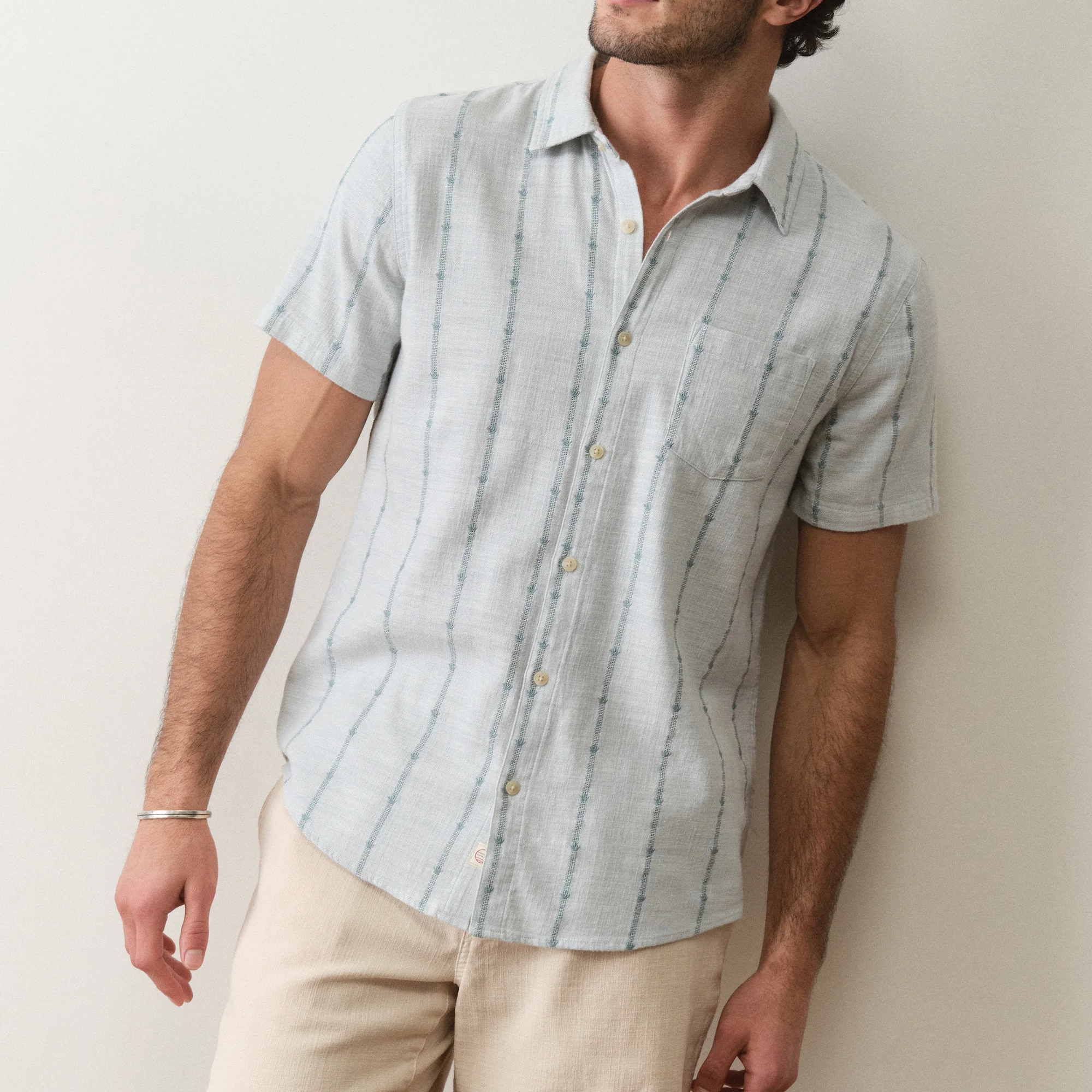 Man wearing a light blue striped shirt against a plain background