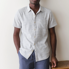Man wearing a short-sleeve button-up shirt and blue pants against a plain background