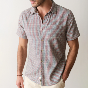Man wearing a patterned short-sleeve shirt against a plain background