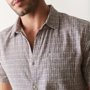 Man wearing a short-sleeve shirt with a subtle pattern on a plain background