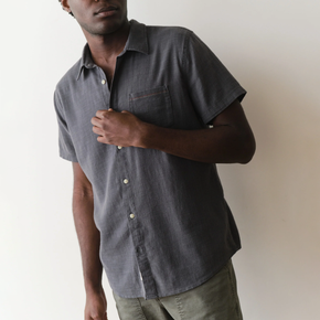 Man wearing a dark blue short-sleeve shirt against a plain background