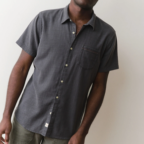Person wearing a dark blue short-sleeve button-up shirt against a plain background
