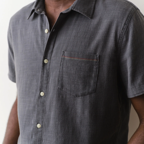 Gray short-sleeve button-up shirt with a pocket on a neutral background