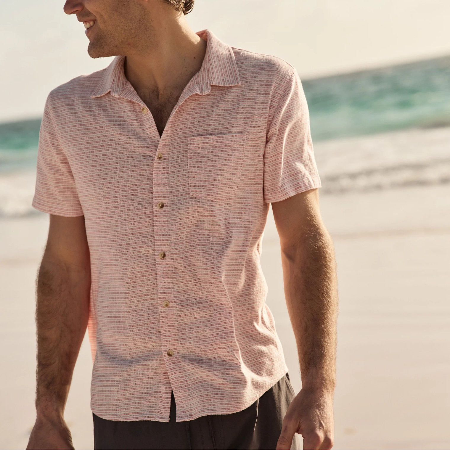 Man wearing a pink checkered shirt on a beach