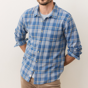 Man wearing a blue plaid shirt with rolled-up sleeves against a plain background