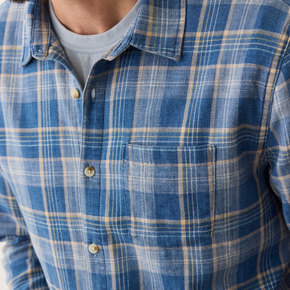 Close-up of a person wearing a blue and beige plaid shirt.