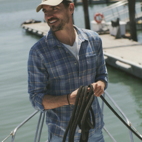 Man holding a rope on a boat with a dock and water in the background